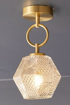 a light fixture with a glass ball hanging from it's center and a metal ring around the base