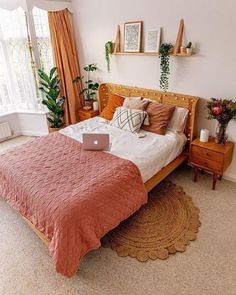 a bed room with a neatly made bed and a laptop computer on the end table