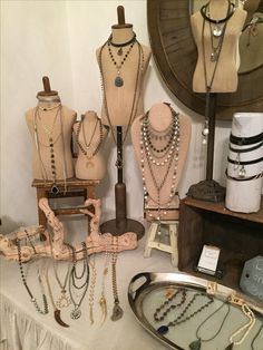 a table topped with lots of necklaces and mannequins