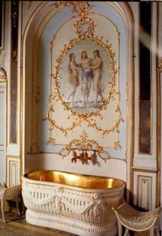 an ornately decorated bathroom with gold and white fixtures, including a bathtub in the center