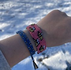 a person's arm with two bracelets on it and snow in the background