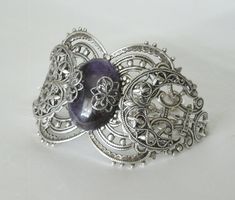 "This beautiful silver plated filigree cuff bracelet has a silver plated triple moon design, amethyst setting with silver plated embellishments and silver plated chain. 6\" long adjustable to 9\" long. Silver plated lobster clasp." Spiritual Decorative Silver Jewelry, Bohemian Antique Silver Bracelets For Gift, Bohemian Antique Silver Bracelets As Gift, Spiritual Silver Decorative Jewelry, Bohemian Antique Silver Bracelets Gift, Silver Gothic Bracelets For Festival, Metal Filigree Cuff Bracelet As Gift, Handmade Gothic Metal Bracelets, Gothic Bangle Bracelet For Gift