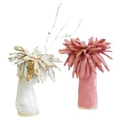 two ceramic vases with flowers in them on a white background, one is pink and the other has gold