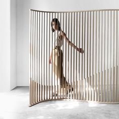 a woman is standing in front of a wooden partition that has vertical bars on it