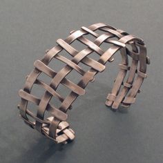 This bracelet is a comprised of a loose network of irregular blackened silver bars. The light, open design and partial darkness of the silver make this ring a classic and exciting piece of jewellery. The bracelet alone is very impressive, but it is also well suited in combination with other pieces from the “Lattice collection. These items and more can also be ordered from our jewellery factory's online shop. . silver - material information. Dimensions: Bracelet width: 1.06 inch, 27 mm Modern Hand Forged Metal Bracelet, Modern Oxidized Cuff Bracelet Bangle, Modern Oxidized Finish Cuff Bracelet Bangle, Modern Oxidized Finish Cuff Bangle Bracelet, Modern Cuff Bracelet With Oxidized Finish, Open Design, Silver Bars, Photo Bracelet, Lattice