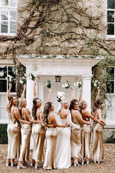 a group of women standing next to each other in front of a white building with vines on it