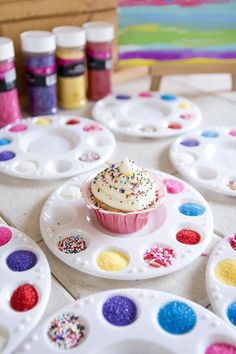 a cupcake is sitting on a plate surrounded by paintbrushes