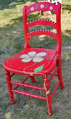 a red chair sitting on top of a grass covered field