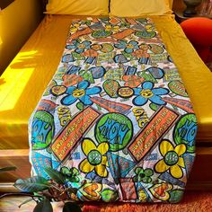 a bed with a colorful comforter on top of it next to a potted plant