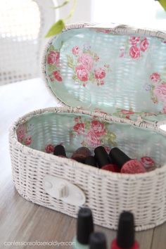 a white wicker box filled with bottles of nail polish sitting on top of a wooden table