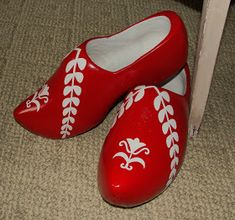 pair of red shoes with white laces sitting on the floor next to a door