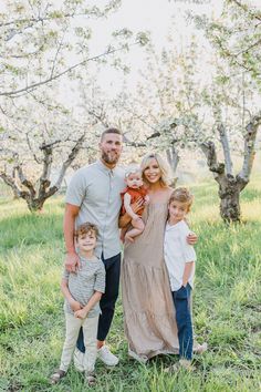 a family posing for a photo in an apple orchard with their toddler's