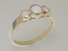 "A Wonderfully simple trilogy ring with a reassuringly thick solid shank. Three Opals all held securely in place with a pinch style flush setting, the Opals measure approx 4.25mm (0.17\") and 2.75mm round(0.11\"). These are Genuine Natural Opals therefore each one has been individually selected for this ring by expert jewelers to ensure they are a good match. The Opals are full of flecks of color which stand out well against the Polished Silver The ring has been Designed & Made in England by tra Flush Setting, Trilogy Ring, Ring Sizes, Engagement Anniversary, Natural Opal, Yellow Rose, Pink Tourmaline, Solid 925 Sterling Silver, Blue Topaz