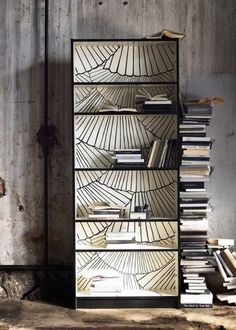 a bookshelf filled with lots of books in front of a wall covered in peeling paint