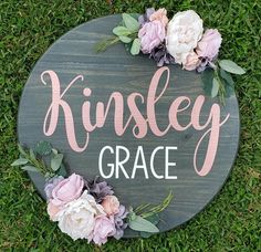 a wooden sign that says kinsley grace with flowers around it on the grass in front of some green grass