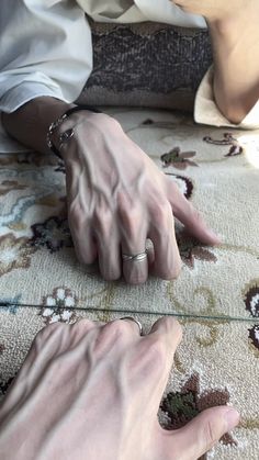 two hands pointing at each other on a rug with flowers in the foreground and one hand holding another's finger