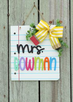 a sign that says, mrs downman hanging on a wooden fence with a bow