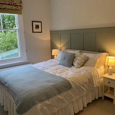 a bed sitting next to a window with two lamps on either side of the bed