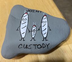 a rock that has been painted to look like two people holding surfboards with the words, don't custoy on it