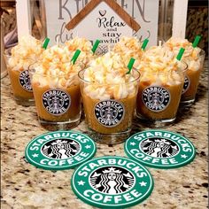 four starbucks drink coasters sitting on top of a counter next to cups filled with coffee