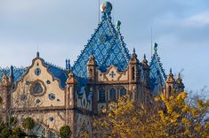 an ornate building with blue and white tiles on it's roof, surrounded by trees