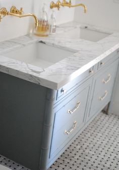 a bathroom with two sinks and gold faucets on the counter top in front of it