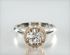 a white and yellow gold engagement ring with an oval center stone surrounded by small diamonds