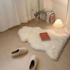 a pair of white slippers sitting on top of a floor next to a book