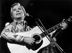 a man holding a guitar and singing into a microphone