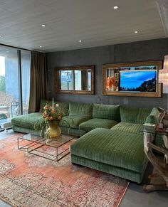 a living room filled with green couches next to a large glass window covered in curtains