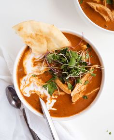 two bowls of soup with bread and garnishes