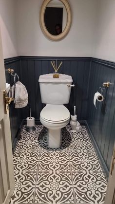 a white toilet sitting inside of a bathroom next to a mirror on the side of a wall