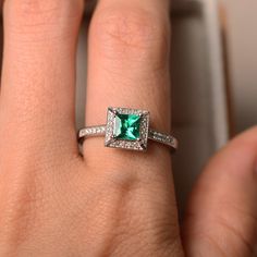 This halo ring features a 5mm princess cut lab emerlad and sterling silver finished with rhodium. Customization is available. It is made by hand, and it will take about 7 days to finish the ring after your payment is completed. Main stone: Lab emerald Emerald weight: Approx 0.60 ct Metal type: sterling silver finished with rhodium Accent stone: cz Customization is available, I also can make it with 14k solid gold (white or yellow or rose) and diamond accent stone, just feel free to contact me. A Princess Cut Diamond Emerald Ring For Promise, Princess Cut Emerald And Diamond Promise Ring, Elegant Emerald Ring With Halo In Cubic Zirconia, Elegant Emerald Cubic Zirconia Ring With Halo, Elegant Emerald Halo Ring With Cubic Zirconia, Silver Princess Cut Emerald Ring For Wedding, Emerald Diamond Halo Promise Ring, Elegant Green Halo Ring With Cubic Zirconia, Emerald Diamond Ring With Halo For Promise