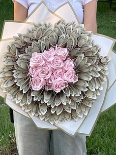 a person holding a bouquet of flowers made out of dollar bills in the shape of a heart