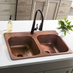 a kitchen sink sitting on top of a counter next to a vase with flowers in it