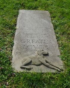 a stone marker in the grass with writing on it that reads great loved and an image of a dog laying down