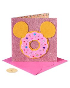 a pink card with a donut shaped like mickey mouse's face on it