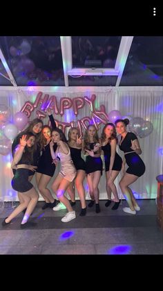 a group of young women standing next to each other in front of a happy birthday sign