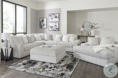 a living room filled with white furniture next to a large window on top of a hard wood floor