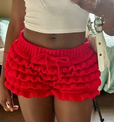 a woman wearing a red ruffled skirt and white tank top is taking a selfie with her cell phone