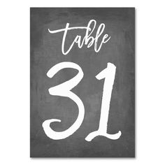 a chalkboard table number sign with the word table 32 written in white on it