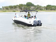 a group of people riding on the back of a white boat in a body of water