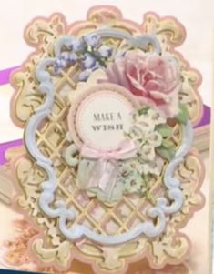 a close up of a greeting card with flowers and ribbon on the front, in an ornate frame