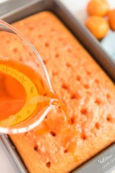 a measuring cup filled with liquid sitting on top of a baking pan next to oranges