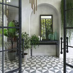 an entryway with black and white tiled flooring, potted plants and mirrors