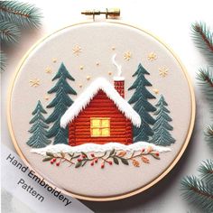 a cross stitch christmas scene with a red cabin in the snow and pine trees on it