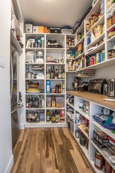 an organized pantry with white shelving and wood flooring is pictured in this image