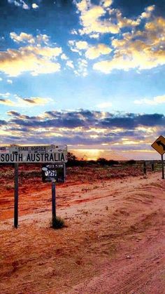 a dirt road with a sign that says south australia in front of a sunset sky