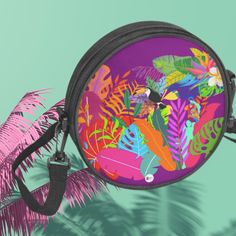 an image of a colorful tropical print purse on a palm tree branch with its reflection in the mirror