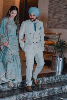 a man in a turban and a woman in a blue dress are walking down the stairs